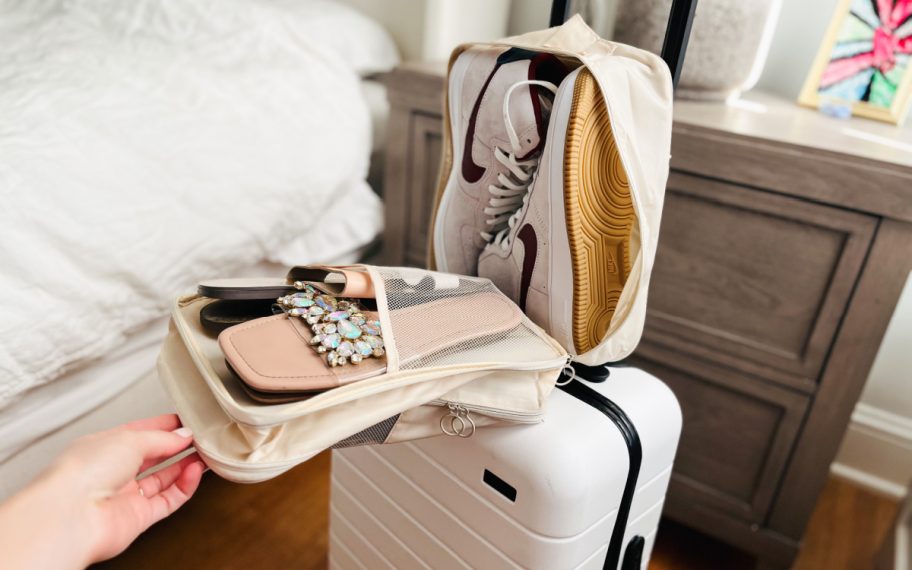 woman's hand opening a Travel Shoe Organizer Bag that attaches to her luggage