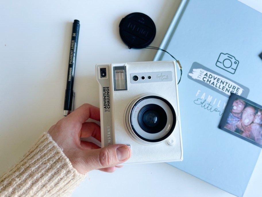 hand holding camera next to photo book