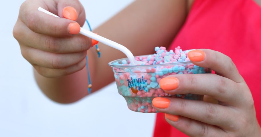 woman holding a cup of blue and red dippin dots which is one of the free things you can get on your. birthday