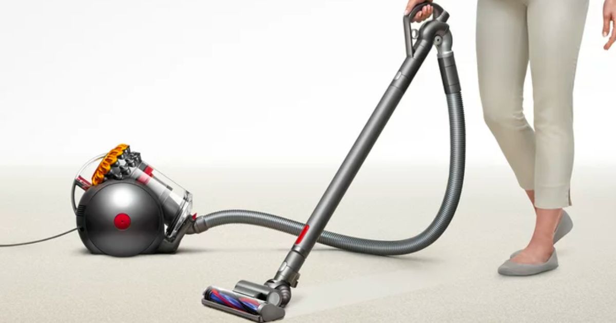 a womans legs as she standing next to a dyson big ball vacuum cleaner