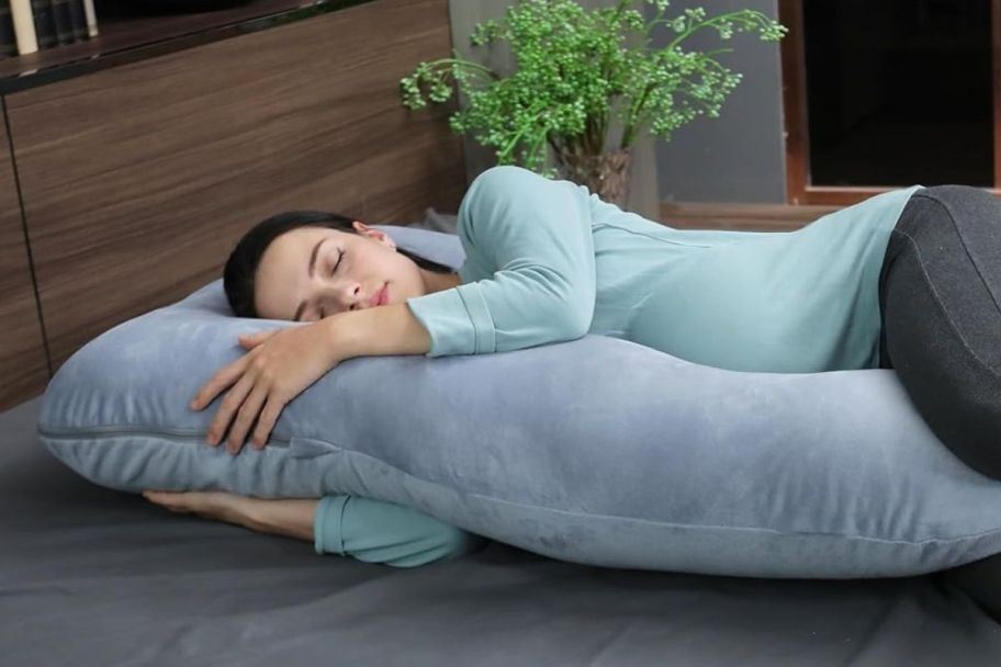 a woman sleeping on a full body pillow