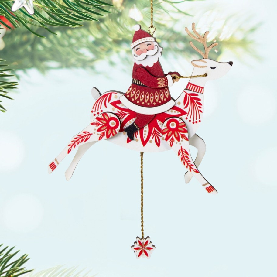 a pull-string Reindeer with Santa riding it Christmas ornament hanging from a tree limb