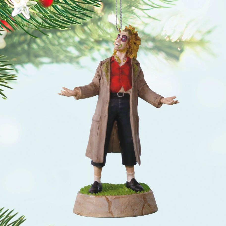 a Beetlejuice Christmas ornament hanging from a tree limb