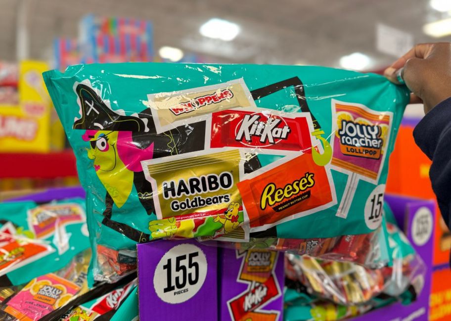 a womans hand holding a 155 count bag of halloween candies