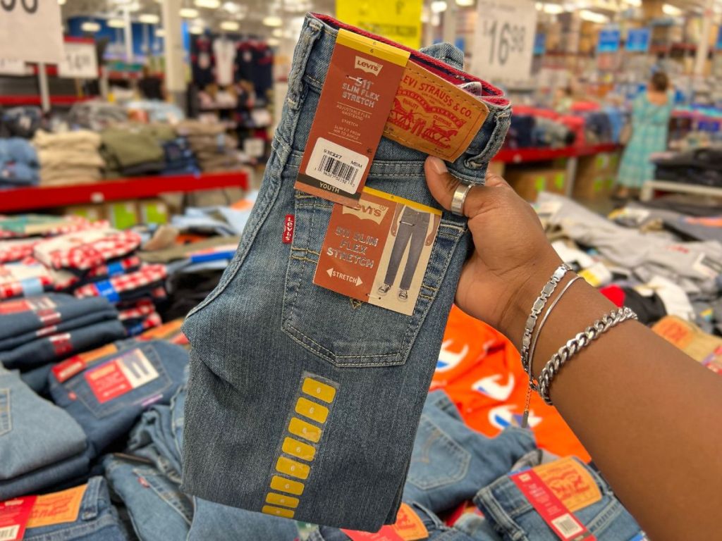 hand holding up pair of Levis youth jeans in store