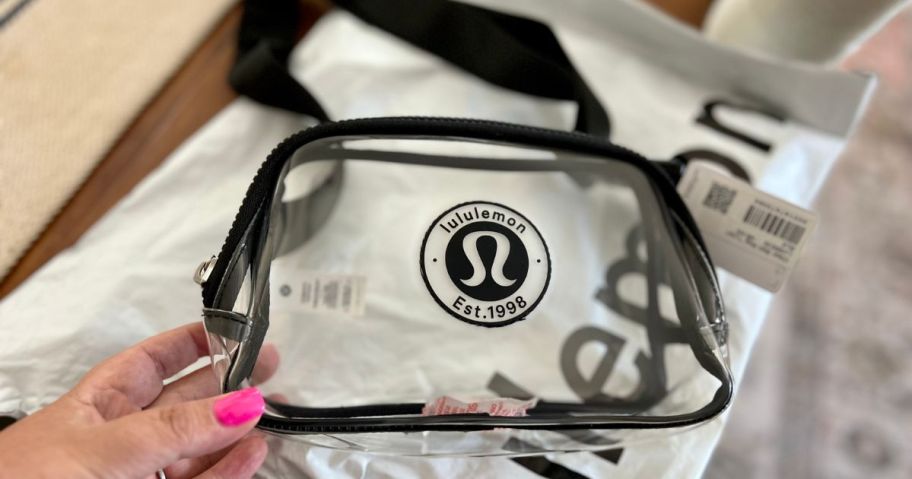 a hand holding a lululemon clear belt bag on counter
