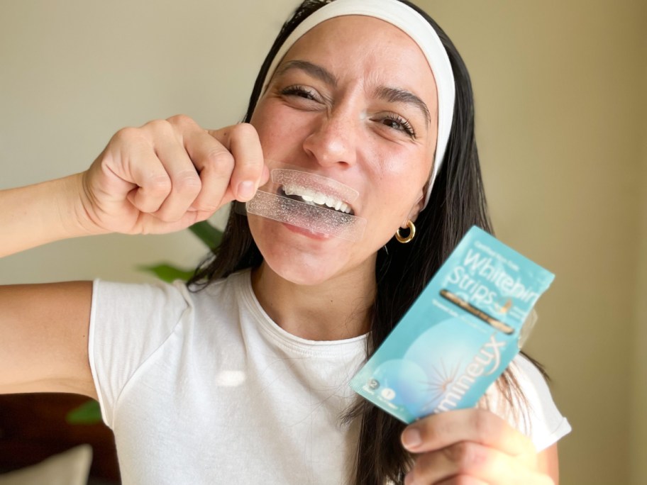 woman holding whitening strips over teeth