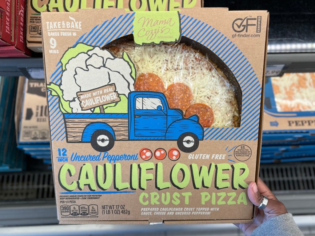holding a boxed cauliflower-crust pizza