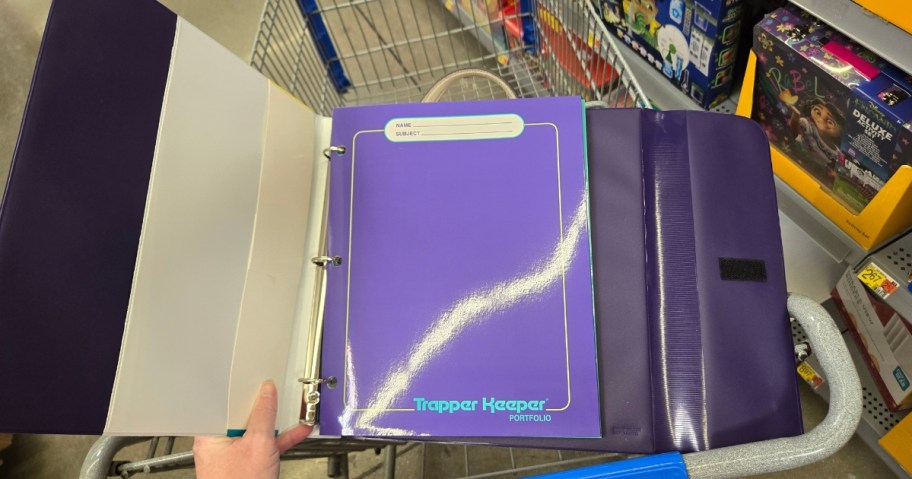 person holding an open Trapper Keeper showing the inside folders and pocket