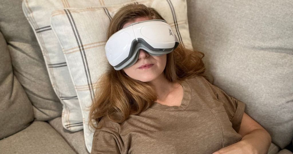 Bob & Brad EyeOasis 2 Heated Eye Mask Massager shown on woman's face who is using it while laying on a couch