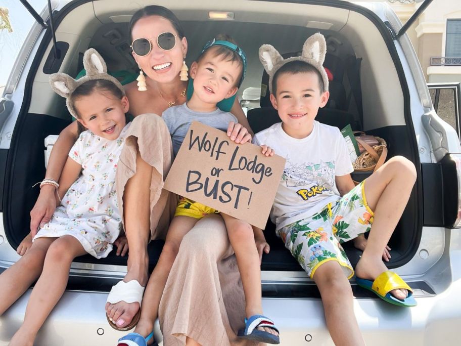 family sitting in truck holding wolf lodge or busy sign