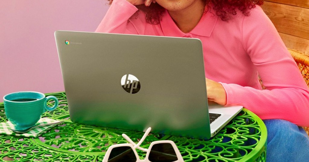 girl in pink shirt working on an hp laptop on a green table
