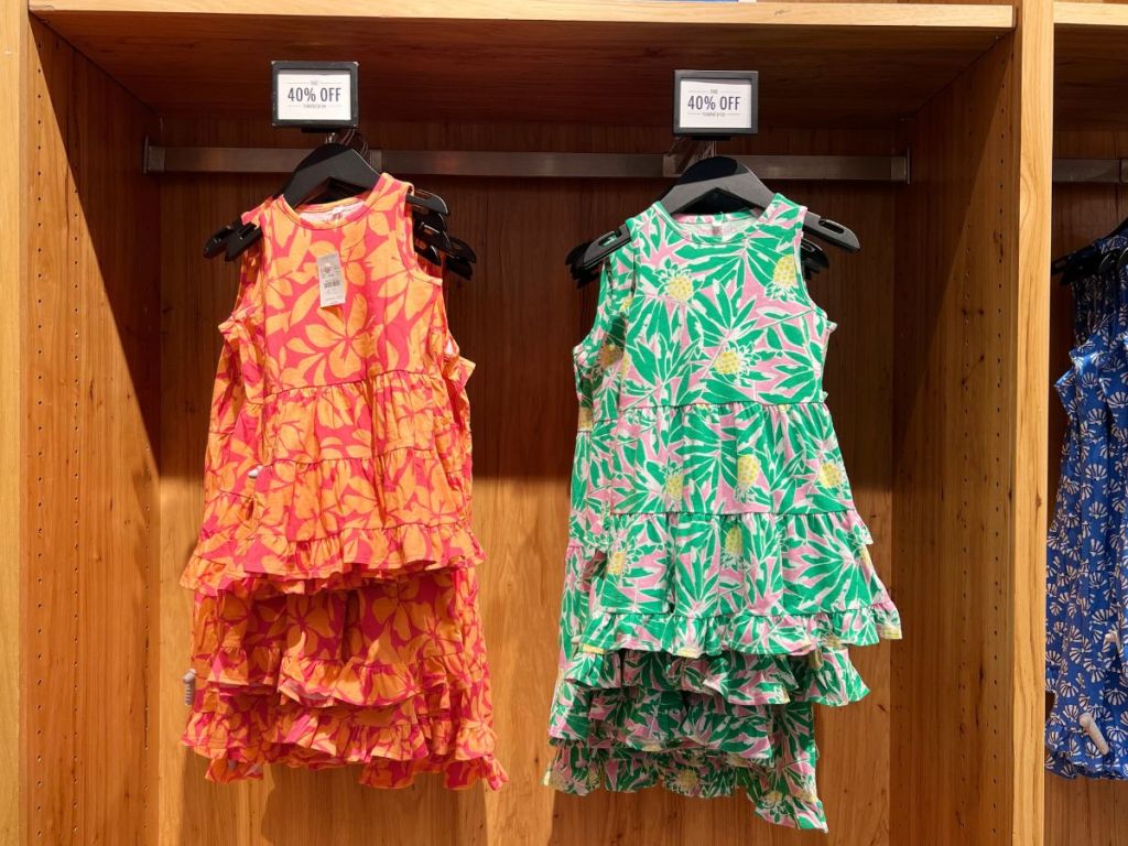 orange and green floral dresses hanging in store 