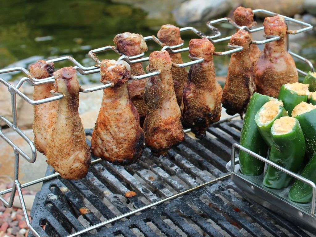 chicken wings and jalapeños cooking on a grill