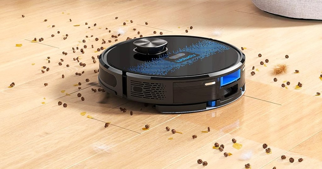black robot vacuum cleaning up pet food on wood floor