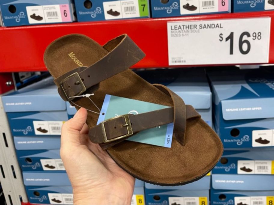 A hand holding a Mountain Sole Ladies Leather Sandal in brown