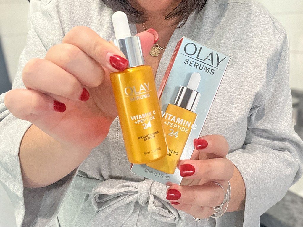 woman holding up yellow bottle of Olay Vitamin C Serum