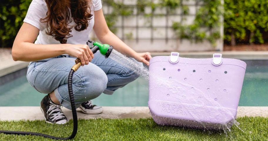 a woman hosing off a Simple modern beach bag in electric purple