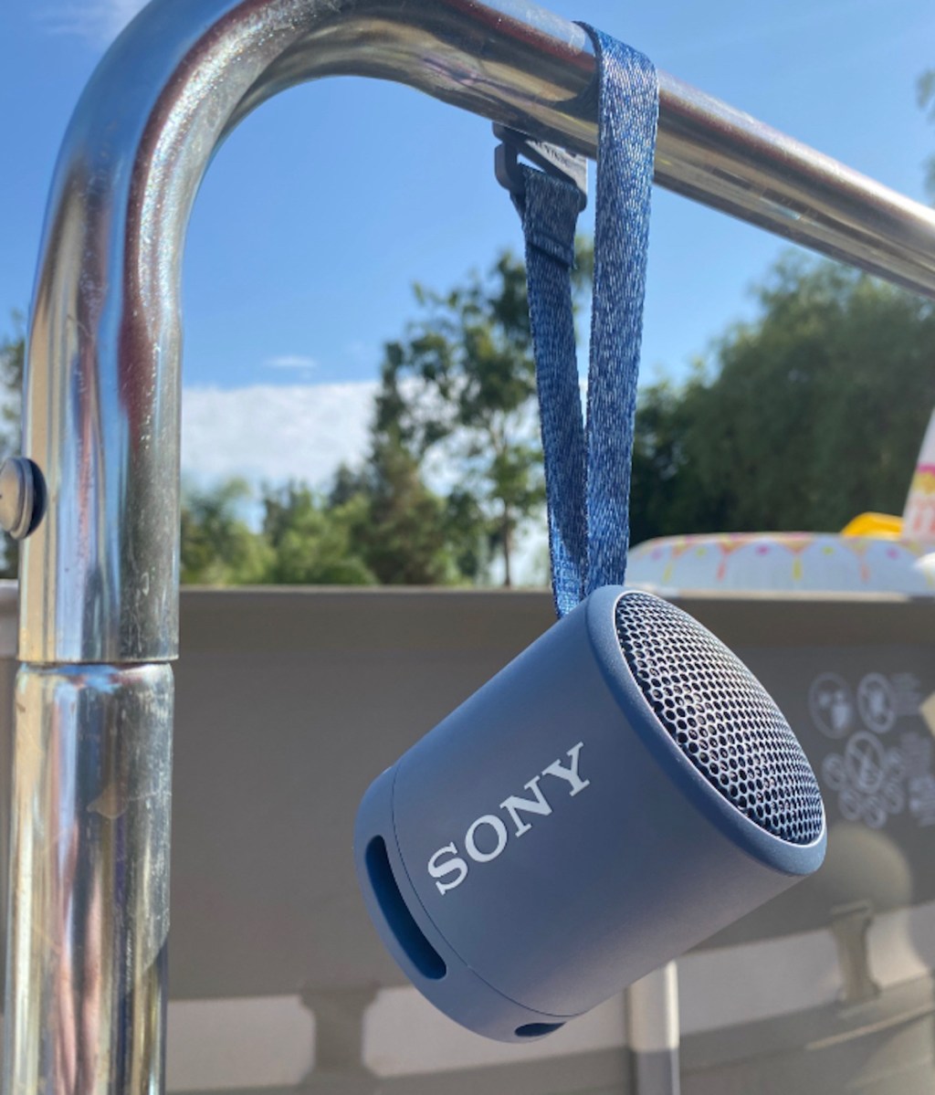small sony speaker hanging from steel pipe outside