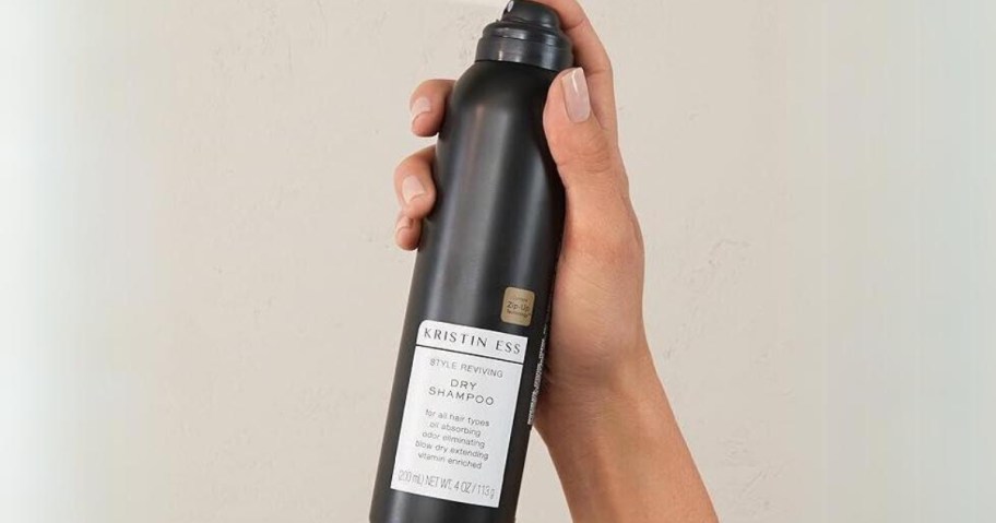 hand holding and spraying a bottle of Kristin Ess Hair Style Reviving Dry Shampoo