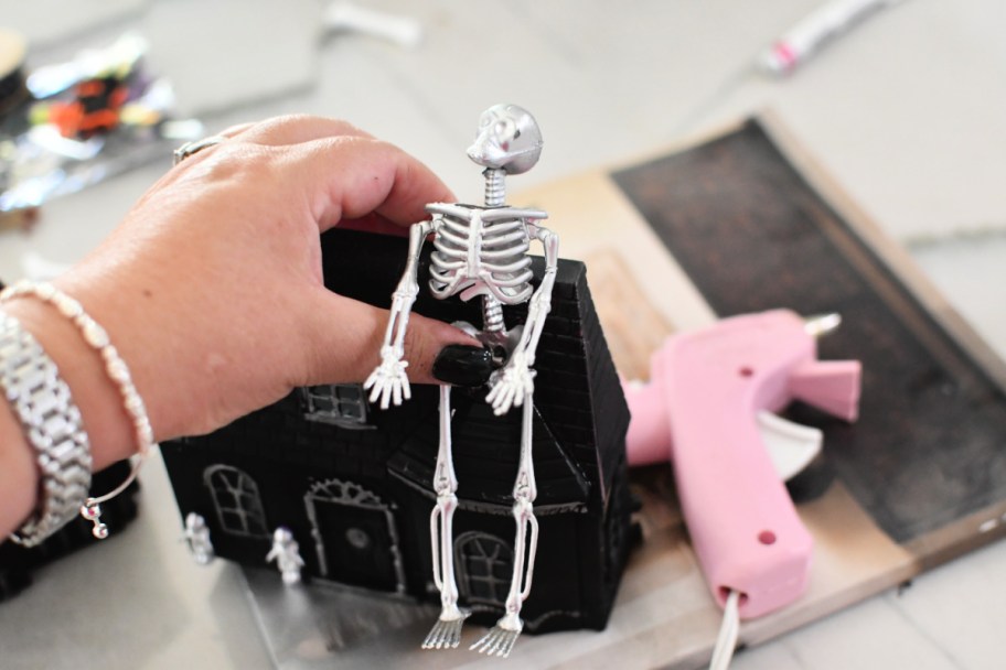 gluing a skeleton to a painted Halloween