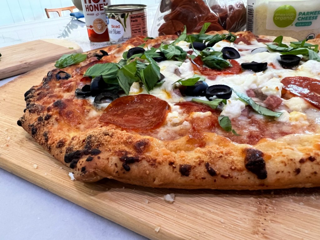 adding basil to a baked pizza