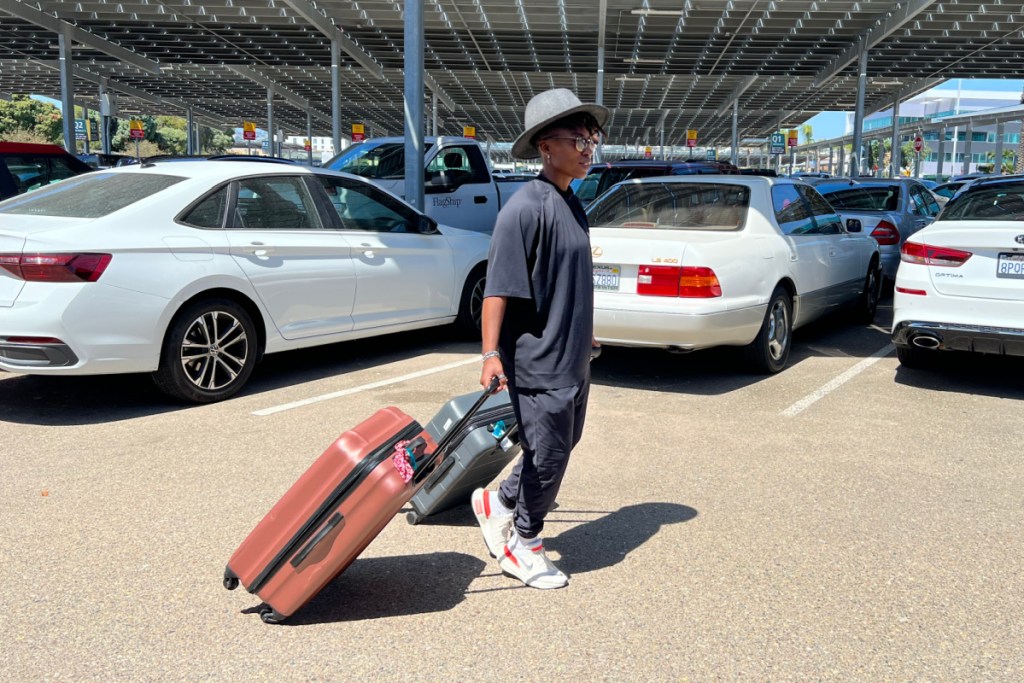 woman pulling luggage through parking lot