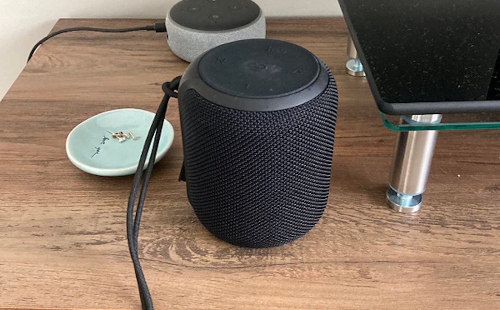 black bluetooth speaker sitting on wood desk