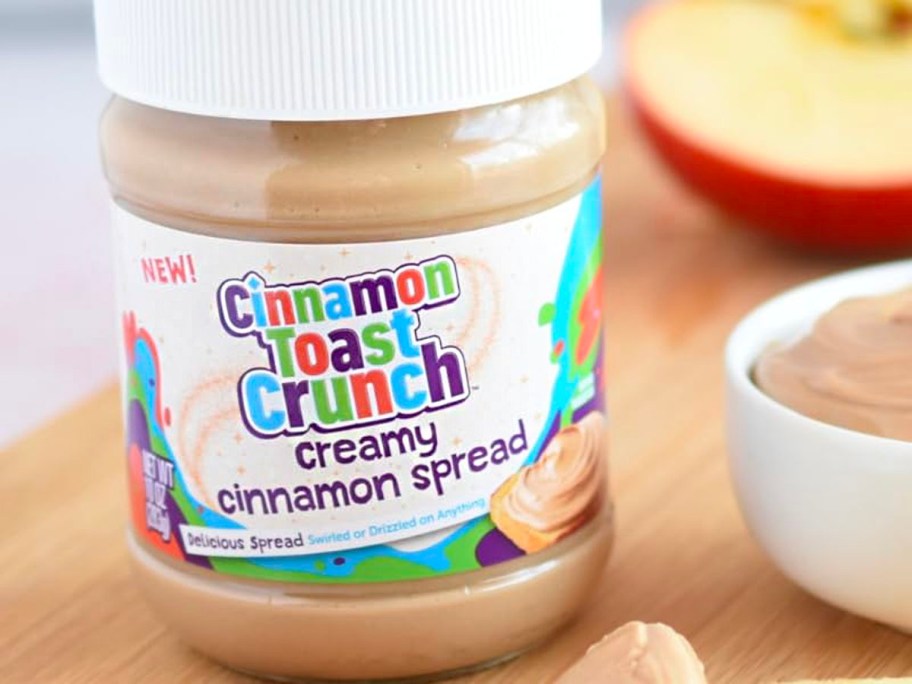 cinnamon toast crunch spread jar on table next to bowl and apple