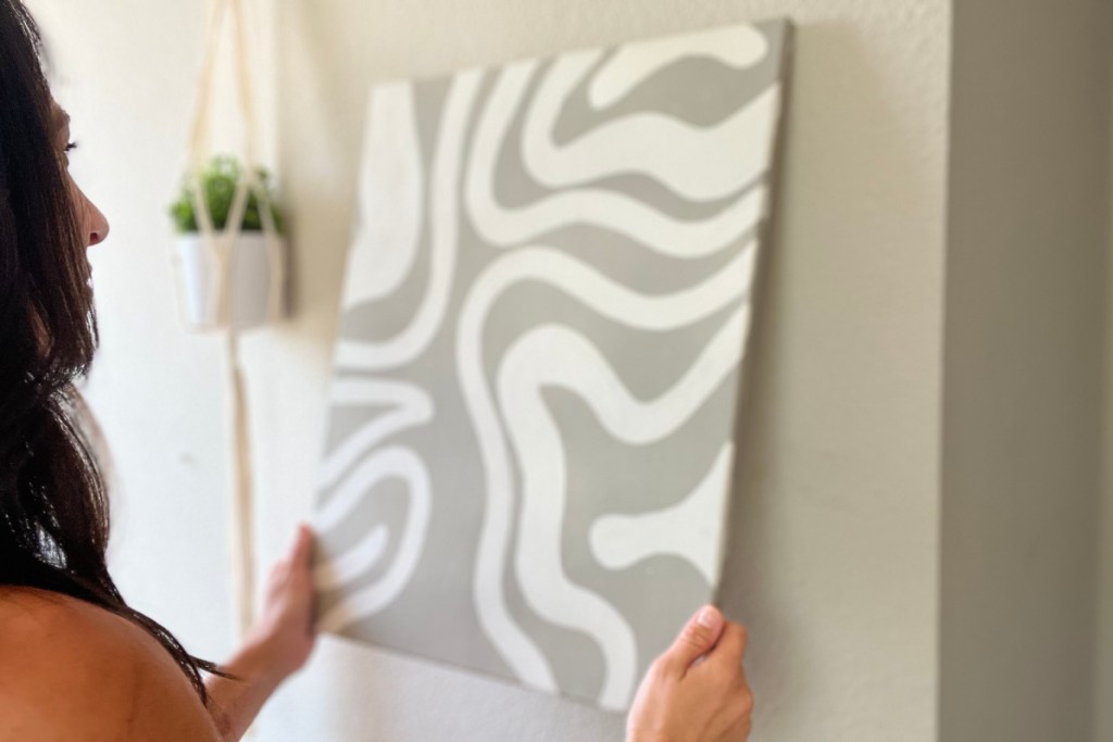 woman hanging canvas on wall