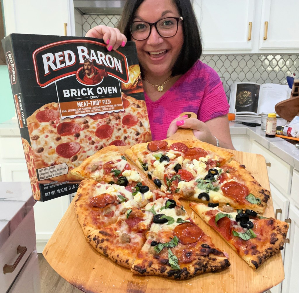 woman holding a cooked frozen pizza on a pizza board 