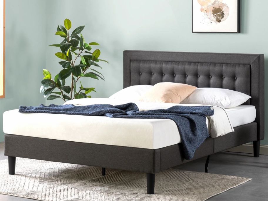 a gray full sized platform bed with tufted headboard