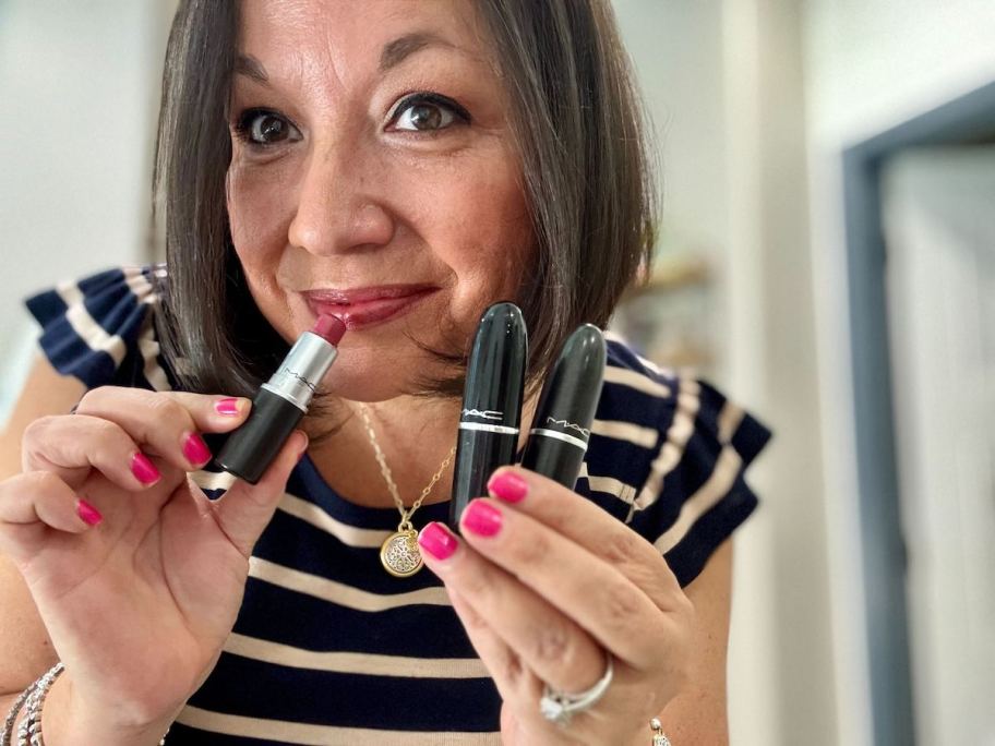 woman holding mac cosmetics in mirror