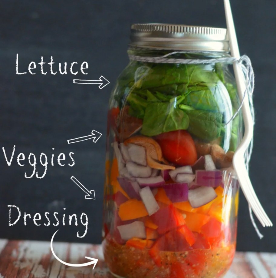 mason jar with salad and dressing inside 