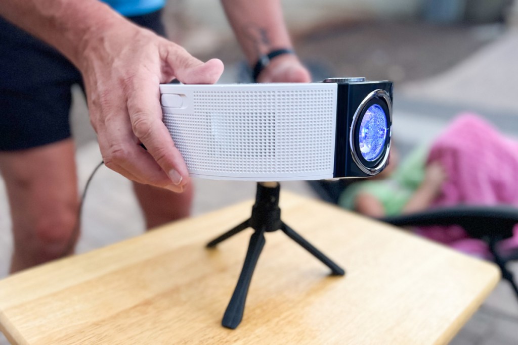 hands setting up round white projector