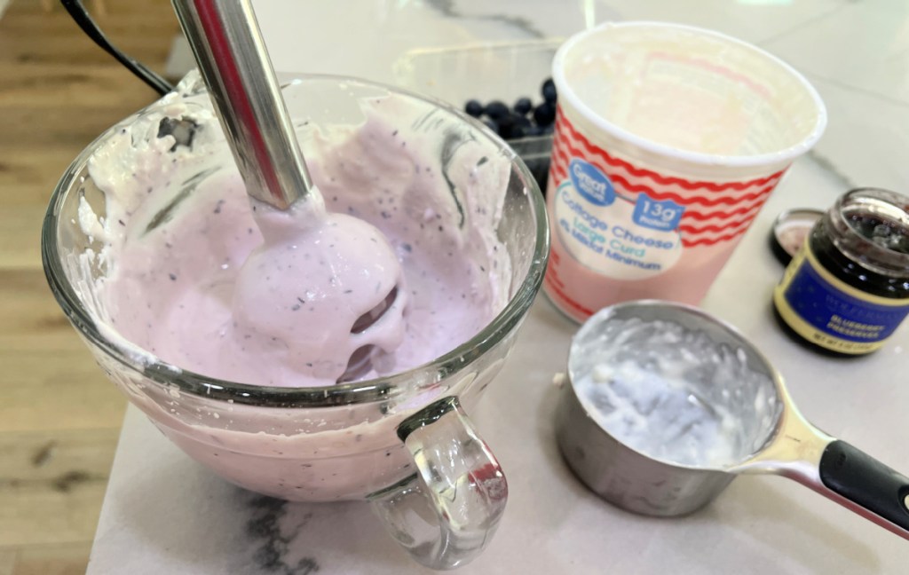 using a hand blender to mix cottage cheese and blueberries