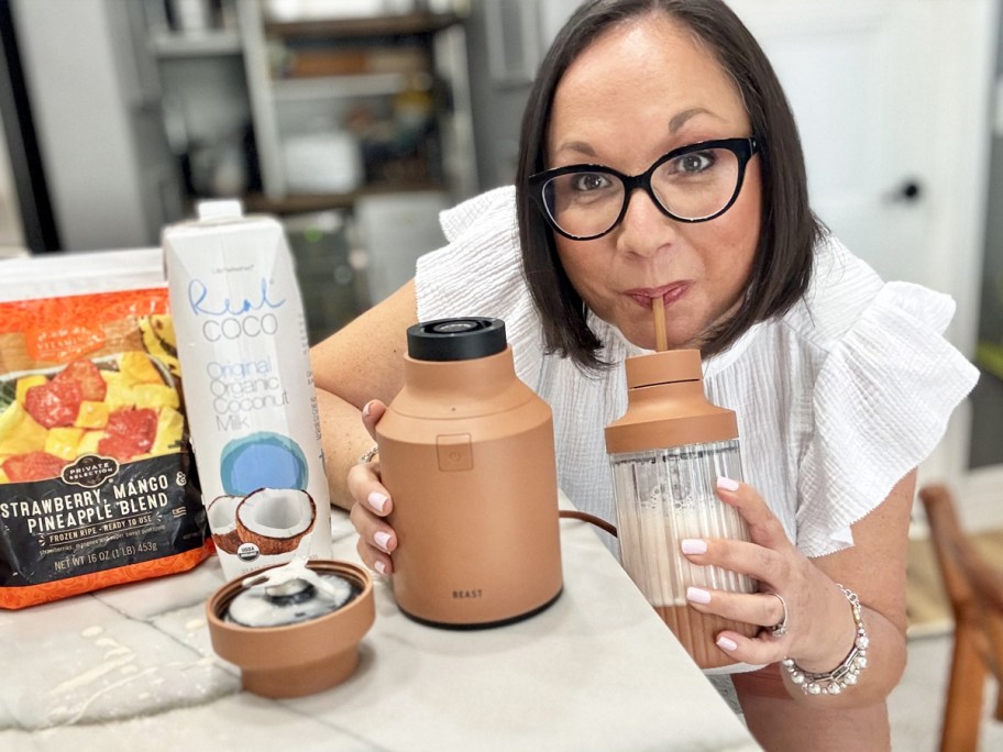 woman sipping smoothie out of blender cup