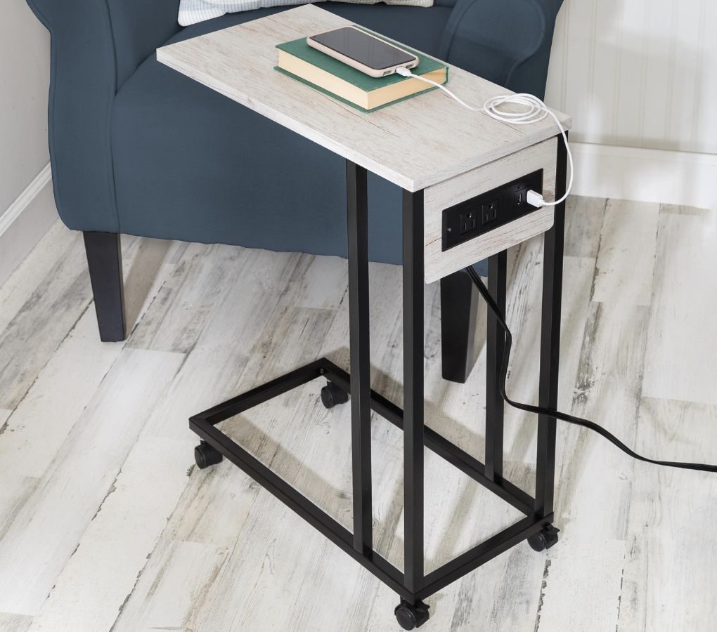 A stock images of a Honey Can Do Side table with built in charging ports next to a chair