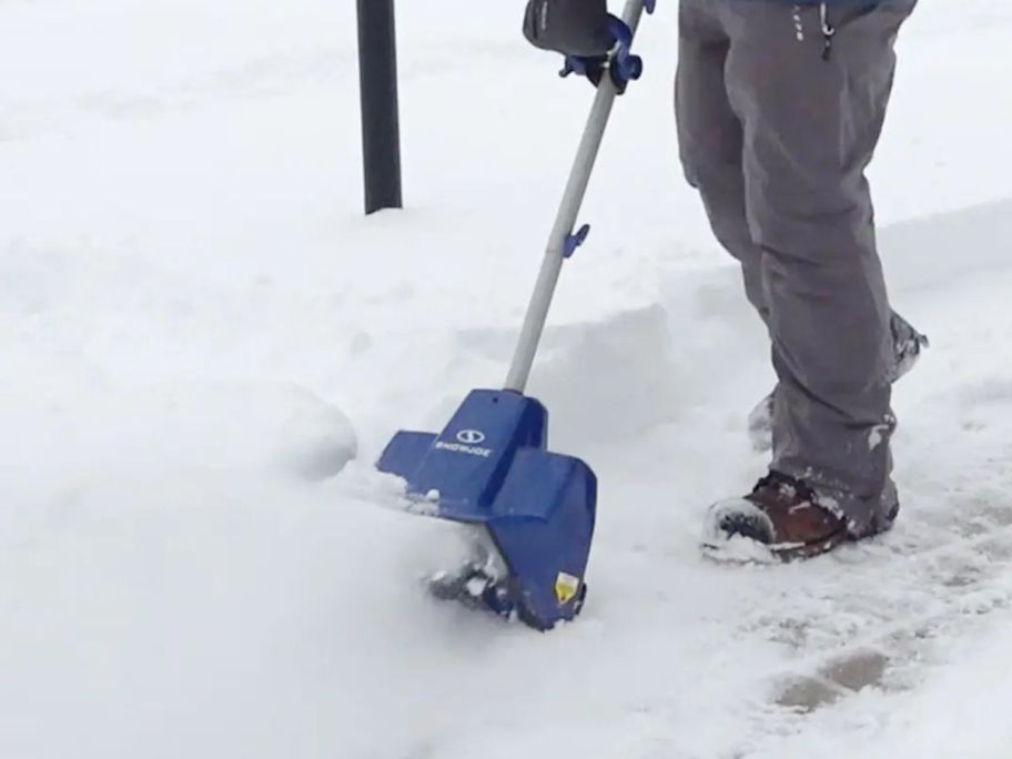 person using Snow Joe 24-Volt Cordless Snow Shovel w/ Bonus Cover outside on sidewalk