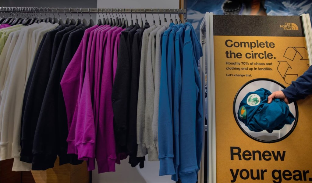 A hand placing clothes in a The North Face Renewed bucket