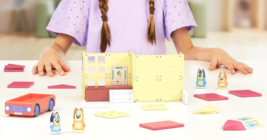 girl with magnetic pieces and bluey figures on table in front of her