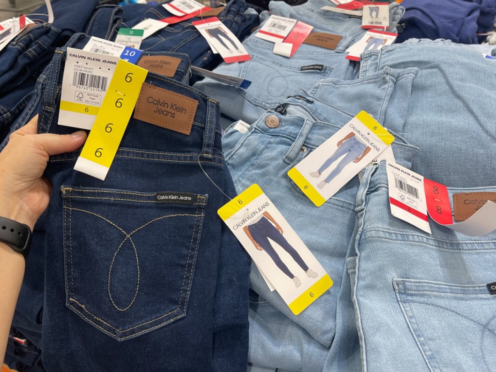 hand holding cabin Klein jeans at costco in light and dark blue jeans