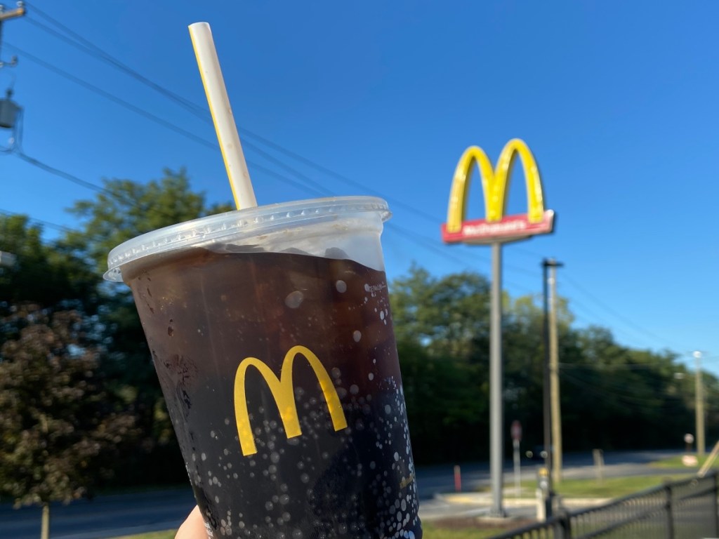 holding a fountain drink outside McDonald's