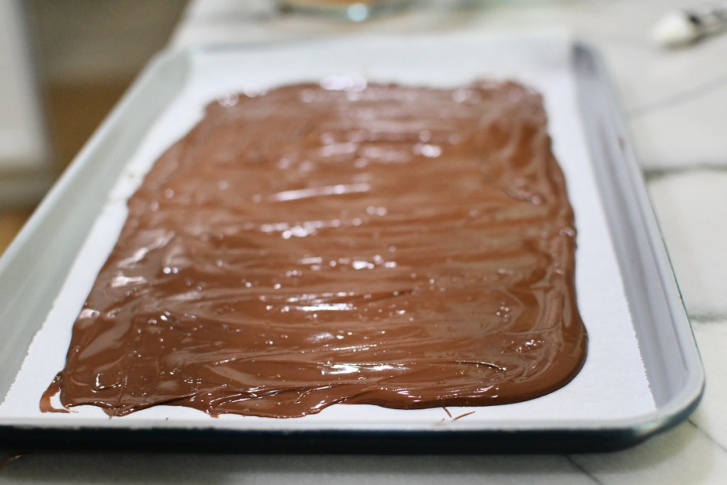 spreading milk chocolate on a sheet pan