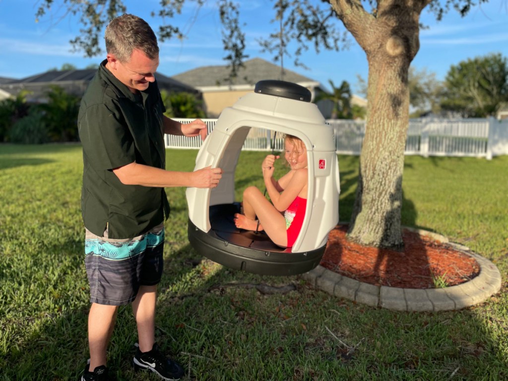 dad pushing girl on rocket ship swing