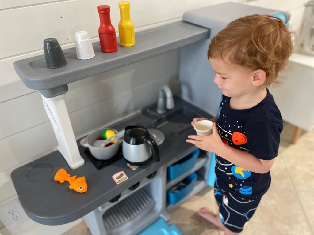 toddler boy playing at play kitchen