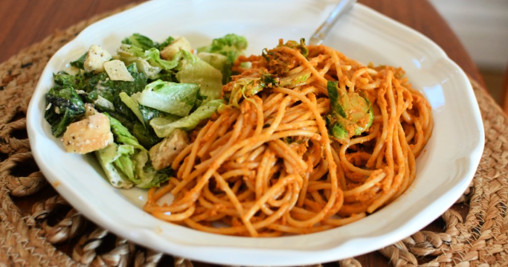 white plate with butternut squash spaghetti and salad