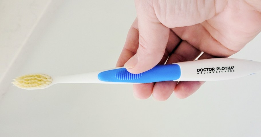 hand holding a blue and white toothbrush over a sink