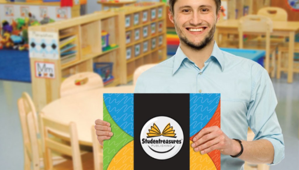 A teacher holding a published book by his students