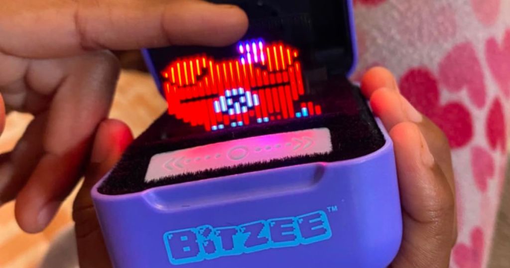 A hand holding and petting a Bitzee digital pet 